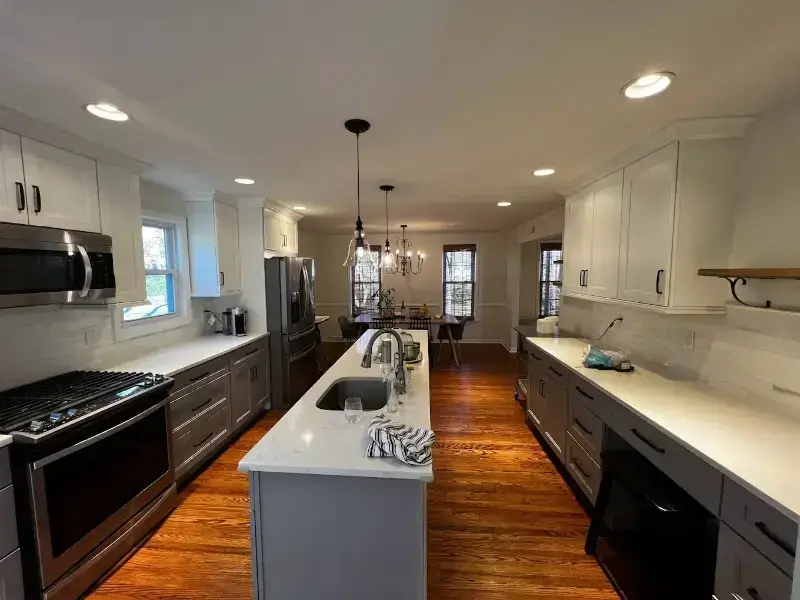 Spacious modern kitchen with white cabinets and wooden floor.